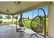 Covered patio featuring two hanging chairs and views of the expansive, lush backyard at 6700 Devlin Ln, Wesley Chapel, FL 33545