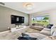 Relaxing living room offers a comfortable sectional sofa, mounted TV, and serene backyard views at 6700 Devlin Ln, Wesley Chapel, FL 33545