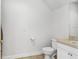 Bright half-bathroom with hardwood floors, toilet, and vanity with beige countertops at 6823 S Kissimmee St, Tampa, FL 33616