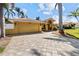 Exterior view of home featuring a wide driveway, garage, terracotta roof, lush lawn, and tropical palm trees at 8014 12Th S Ave, St Petersburg, FL 33707