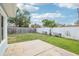 Backyard with a concrete patio and lush green grass surrounded by a white privacy fence at 8439 Boxwood Dr, Tampa, FL 33615