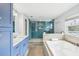 Updated bathroom with blue cabinets, white marble counters, shower with blue tile, and soaking tub at 8439 Boxwood Dr, Tampa, FL 33615