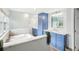 Dual sink bathroom features a soaking tub, stylish fixtures, marble countertops and blue cabinets at 8439 Boxwood Dr, Tampa, FL 33615