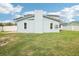 Exterior showing a light blue home with a dark metal roof and a spacious green lawn at 8439 Boxwood Dr, Tampa, FL 33615