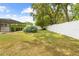 Fenced in backyard featuring green foliage, partial view of screened in patio, and large trees giving plenty of shade at 9069 Gaynor St, Spring Hill, FL 34608