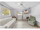 Bright living room with wood-look floors, a ceiling fan, and a large window allowing ample natural light at 9069 Gaynor St, Spring Hill, FL 34608