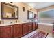 Well-lit primary bathroom features double vanity with wooden cabinets, soaking tub, and decorative mirrors at 10003 Vista Pointe Dr, Tampa, FL 33635