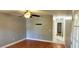 Comfortable bedroom with wood floors, ceiling fan, bright windows, and door to hallway at 10728 Fallen Leaf Ln, Port Richey, FL 34668