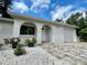 Stunning home with an arched entry, white stucco, a brick driveway, and vibrant landscaping, creating a warm welcome at 11241 Temple Ct, Seminole, FL 33772