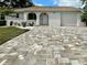 Beautiful house featuring a brick driveway, arched doorway, white stucco, and lush landscaping for inviting curb appeal at 11241 Temple Ct, Seminole, FL 33772