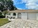 Charming home with white stucco, arched entry, brick driveway, and lush landscaping creating inviting curb appeal at 11241 Temple Ct, Seminole, FL 33772