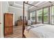 Comfortable main bedroom with wood floors, natural light, en suite bathroom and canopy bed at 11862 Frost Aster Dr, Riverview, FL 33579