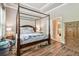 Comfortable main bedroom with wood floors, canopy bed, natural light, and en suite bathroom at 11862 Frost Aster Dr, Riverview, FL 33579