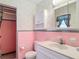 Retro bathroom with pink tiling, white fixtures and decorative wallpaper at 13116 N Oregon Ave, Tampa, FL 33612