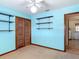 Bedroom features a ceiling fan, closet, shelving, and blue walls at 13116 N Oregon Ave, Tampa, FL 33612