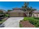 Beautiful single-story home with an attached three-car garage, lush landscaping, and a tiled roof at 13143 Palmilla Cir, Dade City, FL 33525
