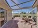 Screened lanai with brick flooring, seating, and view of the golf course at 13143 Palmilla Cir, Dade City, FL 33525
