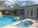 Back exterior of the home with a sparkling pool and hot tub surrounded by a screened enclosure at 14115 Harborwood Dr, Largo, FL 33774