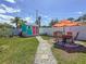 Lush backyard featuring a shed, stone pathway, and outdoor dining area with an orange umbrella at 1734 Shore Acres Ne Blvd, St Petersburg, FL 33703