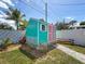 Aqua shed with coral doors and white trim and a stone path on a green lawn at 1734 Shore Acres Ne Blvd, St Petersburg, FL 33703