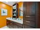 Bathroom boasts double sinks with wood cabinets and white counters, plus a framed picture on the orange wall at 175 1St S St # 1003, St Petersburg, FL 33701