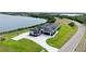 Wide aerial view of a landscaped modern home with a lake backdrop near a paved road at 3610 Gulf City Rd, Ruskin, FL 33570