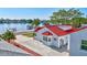 Waterfront home with red roof and a large concrete driveway, palm trees and dock at 4151 Sunrise S Dr, St Petersburg, FL 33705