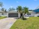 Inviting single-story home featuring a lush lawn, palm trees, and a convenient attached garage at 5731 Denver Ne St, St Petersburg, FL 33703