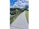 Concrete neighborhood sidewalk runs adjacent to decorative iron fence and community pond at 6293 Bradford Woods Dr, Zephyrhills, FL 33542