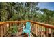 Outdoor wooden deck features a blue chair surrounded by tropical landscaping and natural light at 805 100Th N Ave, St Petersburg, FL 33702
