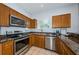 Well-lit kitchen features stainless steel appliances, brown cabinetry, and granite countertops at 805 100Th N Ave, St Petersburg, FL 33702
