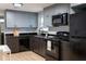 Kitchen featuring black appliances, gray cabinets, black granite countertops, and light wood floors at 8303 N 17Th St, Tampa, FL 33604