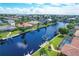 An aerial view of waterfront homes along a canal with boat docks and screened in pools under a sunny blue sky at 890 Coronado Dr, Punta Gorda, FL 33950