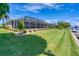 Spacious backyard featuring a screened-in pool and a lush green lawn leading to the waterfront at 890 Coronado Dr, Punta Gorda, FL 33950