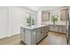 Bright kitchen with gray cabinetry, a white countertop island, stainless steel appliances, and sliding glass doors to the outside at 9535 Coastline Way, Parrish, FL 34219