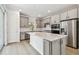 A spacious kitchen featuring gray cabinets, stainless steel appliances, a kitchen island with a white countertop, and a sliding glass door at 9535 Coastline Way, Parrish, FL 34219