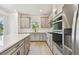 Modern kitchen featuring stainless steel appliances, gray cabinetry, a white backsplash, and a kitchen island with a cooktop at 9535 Coastline Way, Parrish, FL 34219