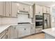 Modern kitchen with stainless steel appliances, gray cabinets, a white subway tile backsplash, and a cooktop on the counter at 9535 Coastline Way, Parrish, FL 34219