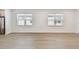 Bright living room with two windows and laminate wood floors, adjacent to a kitchen area at 9535 Coastline Way, Parrish, FL 34219