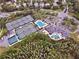 Aerial view of tennis courts, a swimming pool, a clubhouse, and a parking lot surrounded by green trees at 10130 Deercliff Dr, Tampa, FL 33647