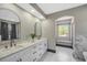 Bright bathroom featuring double vanity, arched mirrors, and window seating area at 10130 Deercliff Dr, Tampa, FL 33647