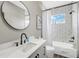 Well-lit bathroom with subway tile walls, a modern vanity, and a round black mirror at 10130 Deercliff Dr, Tampa, FL 33647