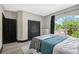 This bedroom has a large window with backyard views and features black trim, gray walls, and wood-look flooring at 10130 Deercliff Dr, Tampa, FL 33647