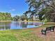 Picturesque pond view with a bench, mature trees, and homes in the background under a sunny sky at 10130 Deercliff Dr, Tampa, FL 33647