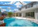 Backyard pool area with a screened enclosure featuring red flowers and clear blue skies at 10130 Deercliff Dr, Tampa, FL 33647