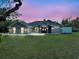 Inviting single-story home exterior with lush green lawn, dusk sky, and elegant stone-accented entry at 11268 Shivering Owl Ave, Weeki Wachee, FL 34614