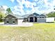 Well-manicured front yard with a gray home featuring stone accents and a vibrant blue double door at 11268 Shivering Owl Ave, Weeki Wachee, FL 34614