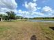 Backyard view of a pond surrounded by a grassy lawn, trees, and blue sky at 12604 Montford Ln, Riverview, FL 33579