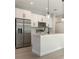 Close-up of the bright, modern kitchen island and stainless steel appliances with pendant lighting at 13451 Kaplan Ter, Port Charlotte, FL 33981
