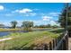 Tranquil canal view bordered by lush green grass and a wooden fence at 1422 Pinebrook Dr, Clearwater, FL 33755